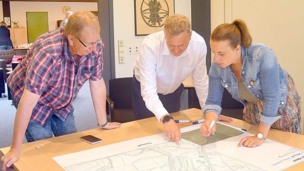 Timmels Ortsbürgermeisterin Silke Bergmann und Ortsratsmitglied Stefan Bender (links) markieren zusammen mit Till de Buhr von der Gemeinde Großefehn ihre Ideen auf einer Landkarte von Timmel. Foto: Gerd-Arnold Ubben