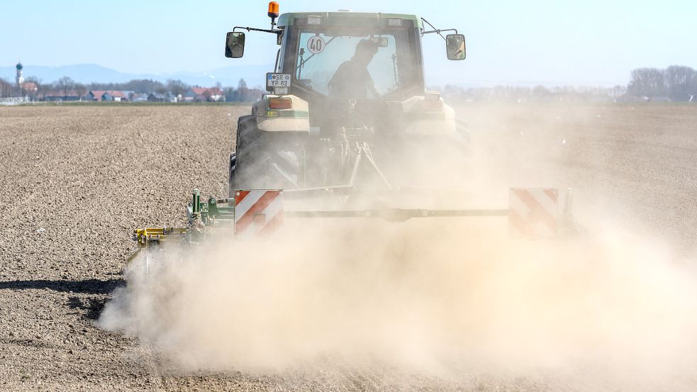 Ein Landwirt wirbelt mit seinem Traktor beim Bearbeiten eines Feldes Staub auf. Foto: DPA