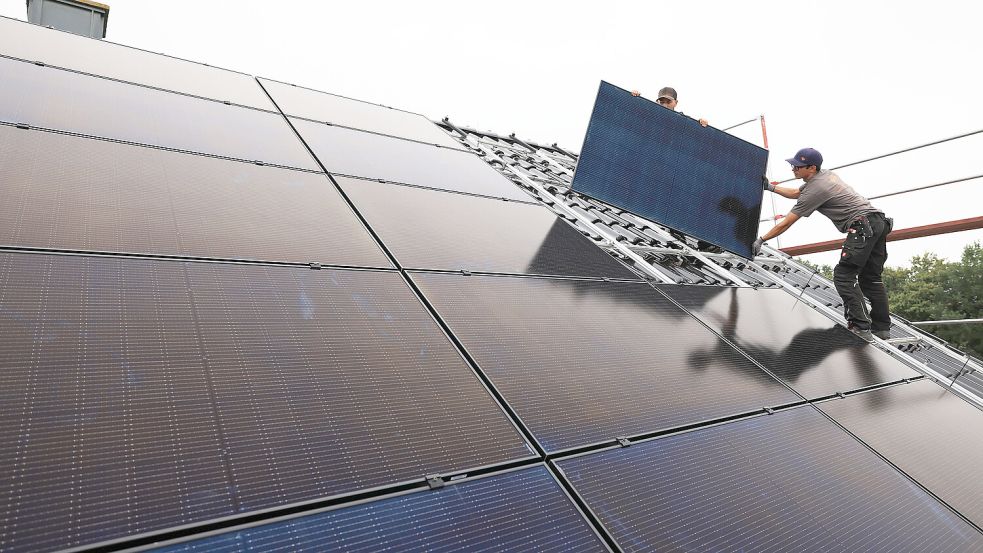 Handwerker montieren auf dem Dach eines Wohnhauses Solarmodule. Foto: DPA