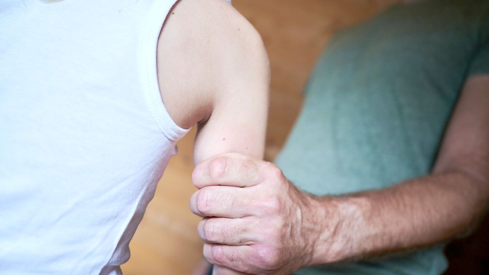 Ein Mann greift den Arm eines Kindes. Foto: DPA
