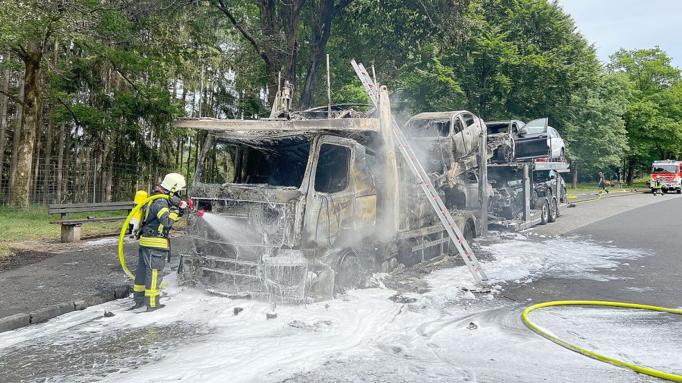 Einsatzkräfte der Feuerwehr bei Löscharbeiten an einem ausgebrannten Autotransporter. Der Brand war vom Führerhaus auf die geladenen E-Autos übergesprungen. Foto: DPA