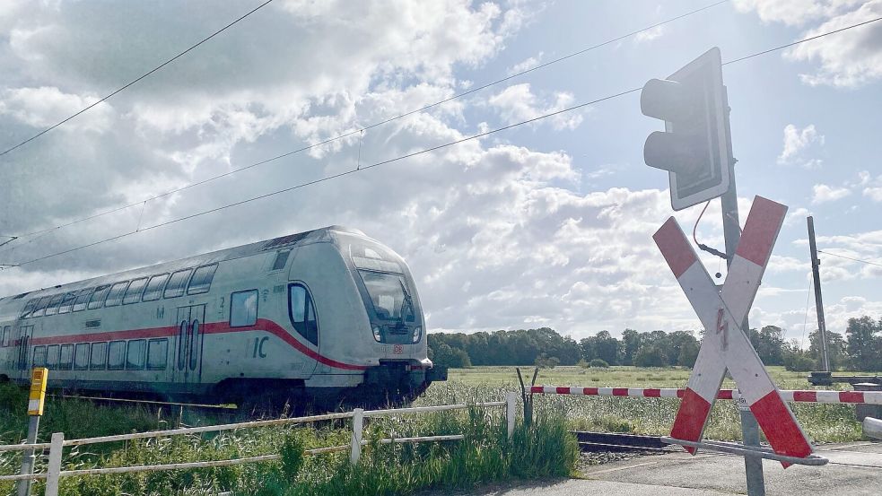 Ein Zug nähert sich dem Bahnübergang mit der provisorischen Lichtzeichenanlage, die jedoch offensichtlich nie zum Einsatz kam. Stattdessen nutzt ein Streckenposten die vorhandene Anrufschranke. Per Knopfdruck an dem gelben Kasten (links im Bild) wird ein Mitarbeiter im Stellwerk gebeten, die Schranken zu öffnen. Foto: Holger Janssen