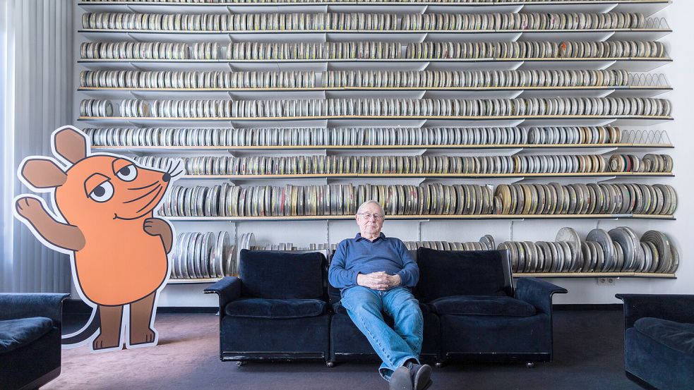 Armin Maiwald, Filmemacher, Autor und Miterfinder der „Sendung mit der Maus“ sitzt auf einem Sofa in seinem Büro vor zahlreichen Filmrollen. Foto: picture alliance/dpa / Rolf Vennenbernd