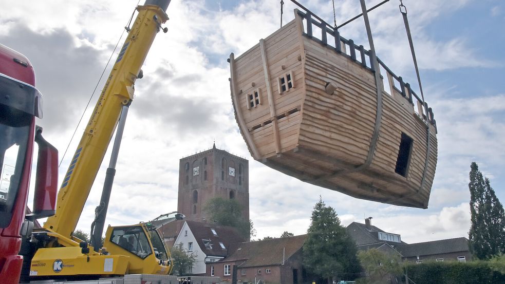 Kommt eine Kogge geflogen: Ein Autokran hievte das tonnenschwere Spielschiff aus Holz auf das Grundstück Am Markt 13 in Marienhafe. Foto: Thomas Dirks
