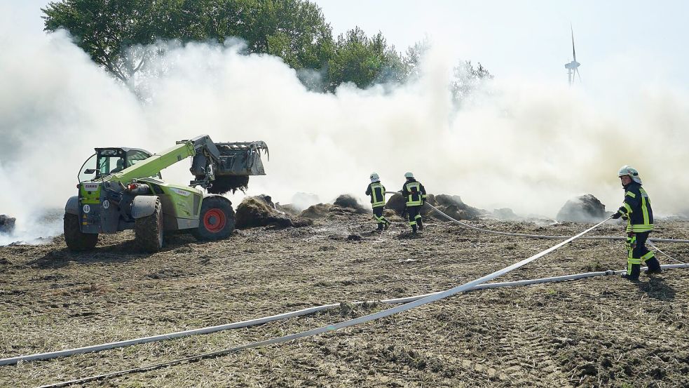 Mit einem Teleskoplader wurden die brennenden Ballen auf ein Feld transportiert. Foto: Feuerwehr