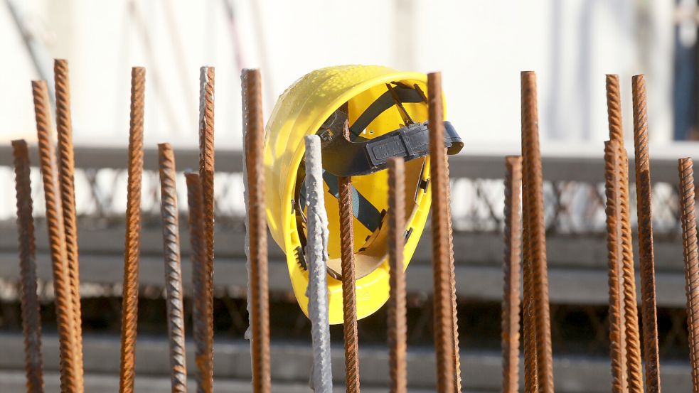 Ein Bauhelm hängt an Fundament-Stangen. In der Kreisverwaltung fehlt es an Bauingenieuren. Foto: DPA