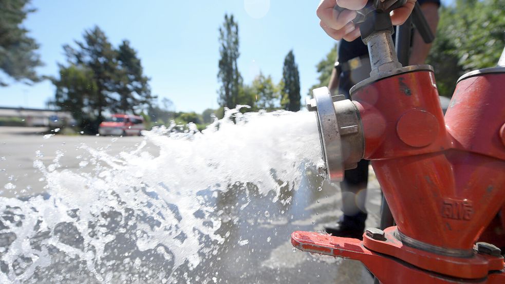 Wasser fließt durch ein Standrohr aus einem Hydranten. Foto: Arne Dedert/DPA