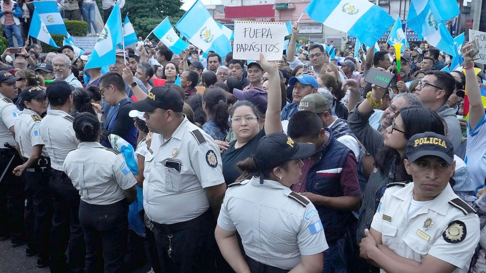Während einer Demonstration in Guatemala-Stadt hält eine Frau ein Schild mit der Aufschrift „Parasiten raus“ in die Höhe. Tausende Menschen protestieren in dem lateinamerikanischen Land gegen die Generalstaatsanwaltschaft. Foto: Moises Castillo/AP/dpa