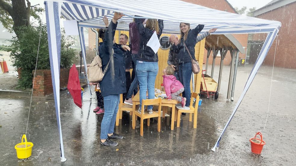 Rette sich wer kann: Bei einem Regenguss flüchteten einige Besucher unter ein Pavillon und sicherten dieses zugleich. Foto: Britta Albers