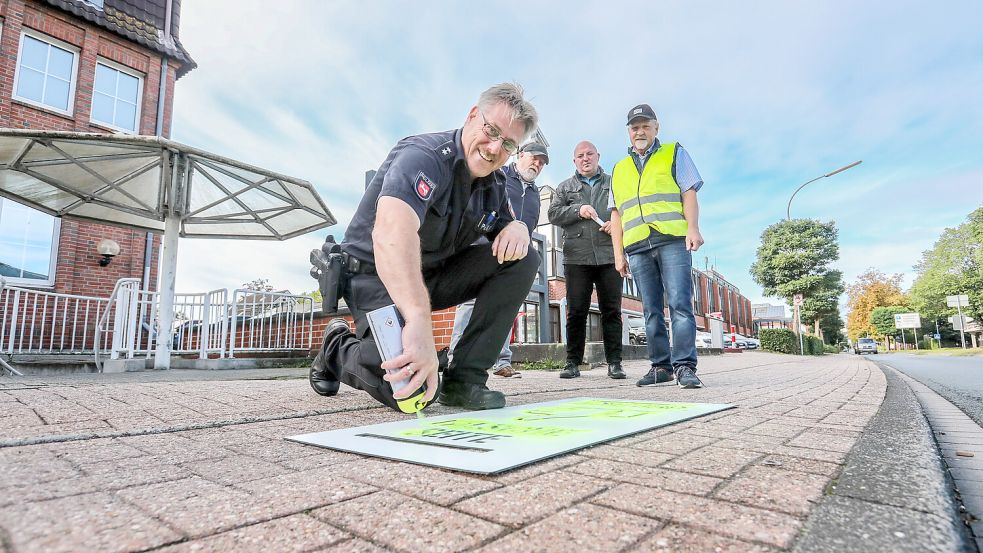 Ewald Einnolf sprüht einen Hinweis auf den Radweg. Im Hintergrund (von links): Wilhelm Doden, Helmut Lücht und Hans-Friedel Walther. Foto: Romuald Banik