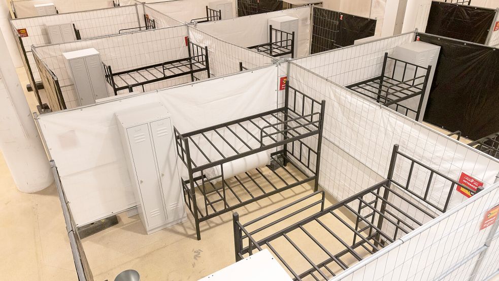 Stockbetten und Spinde stehen zwischen Sichtschutzzäunen in einer Flüchtlingsunterkunft. Wenn die Geflüchteten auf die Städte und Gemeinden verteilt werden, soll nach Möglichkeit angemieteter Wohnraum zur Verfügung stehen. Der Wohnungsmarkt ist allerdings angespannt. Foto: Philipp von Ditfurth/dpa