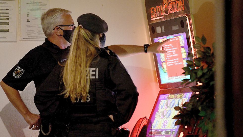 Ein Mitarbeiter des Ordnungsamtes und eine Polizistin sehen sich während einer Razzia gegen Clankriminalität im August 2020 in Essen einen Spielautomaten an. Foto: DPA