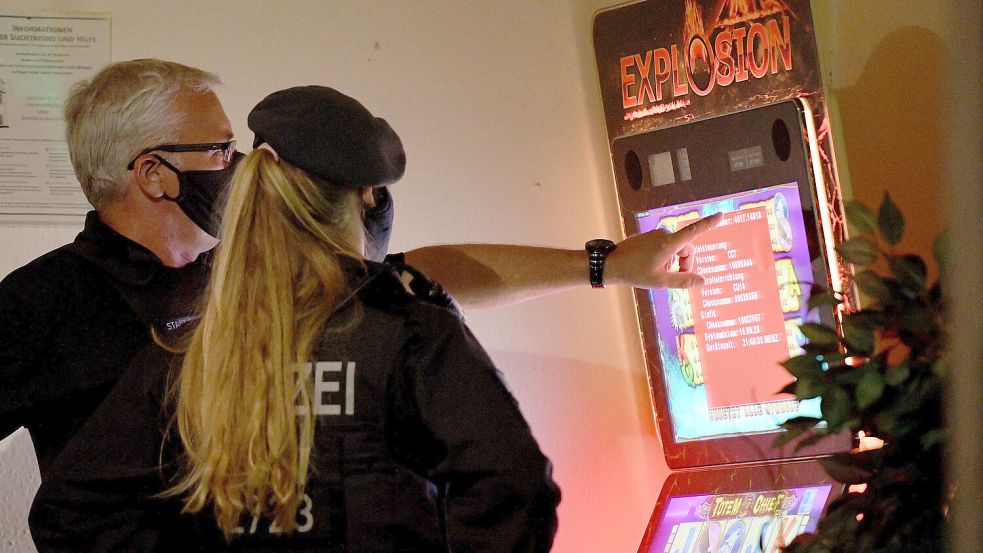Ein Mitarbeiter des Ordnungsamtes und eine Polizistin sehen sich während einer Razzia gegen Clankriminalität im August 2020 in Essen einen Spielautomaten an. Foto: DPA