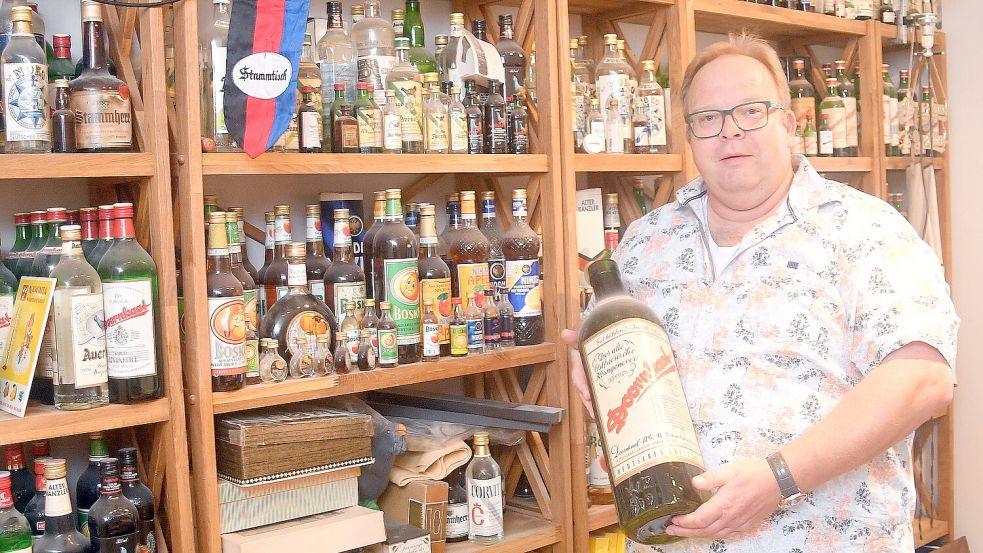 Lothar Clemen vor einem seiner Regale mit Doornkaatprodukten wie „Corvit“, „Auerbach“, „ Stammherr“. Fotos: Gerd-Arnold Ubben