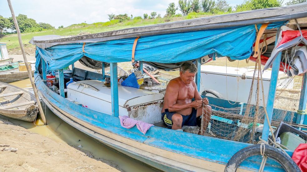 Ein Fischer sitzt fast im Trockenen in seinem Boot und flickt ein Netz. Die Dürre bereitet den Flussbewohnern nicht nur Schwierigkeiten beim Fischen, sondern auch beim Verkehr. Dörfer sind in der Region über die Flüsse vernetzt. Foto: Aguilar Abecassis/dpa