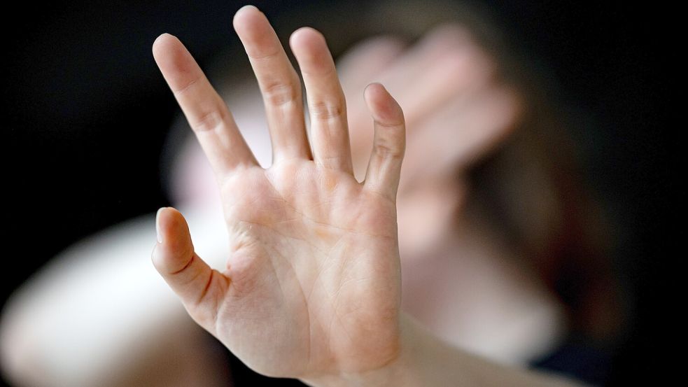 Eine Frau hält sich schützend eine Hand vors Gesicht. Foto: Fabian Sommer/DPA