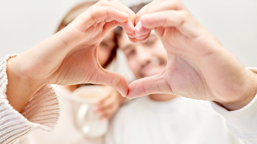 Hands, heart and love with a couple in their home together, bonding for romance or affection while dating. Hand sign, ro Foto: IMAGO/Zoonar.com/Kasper Ravlo