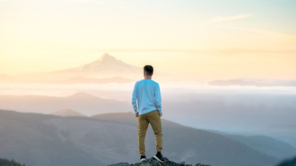 Ein Mann steht auf einem Gipfel. Nach seiner Krebs-Diagnose beginnt der 19-jährige Zack Logan zu leben. Foto: Unsplash/Tim Bogdanov
