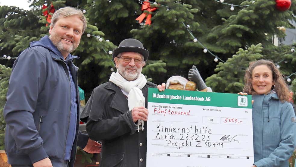 KV-Vorsitzender Udo Hippen (von links), Heinz-Wilhelm Schnieders und Anna de Oliveira bei der Spendenübergabe auf dem Auricher Weihnachtszauber. Foto: Heino Hermanns