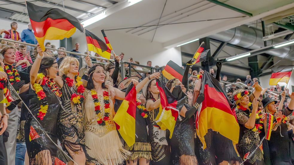 Ausgestattet mit Fahnen und anderen Fan-Artikeln in den Nationalfarben jubelten Zuschauer und Spieler in Marienhafe für das Grußvideo. Foto: Folkert Bents