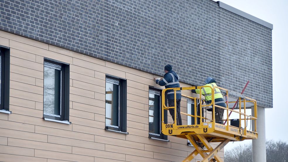 Handwerker bringen am Gebäude des neuen E-Center in Marienhafe die Außenverkleidung an. Foto: Thomas Dirks