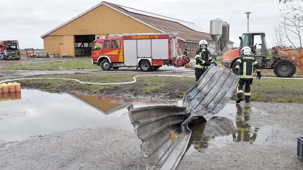 Feuerwehrleute ziehen ein Blechteil aus der Halle. Foto: Thomas Dirks