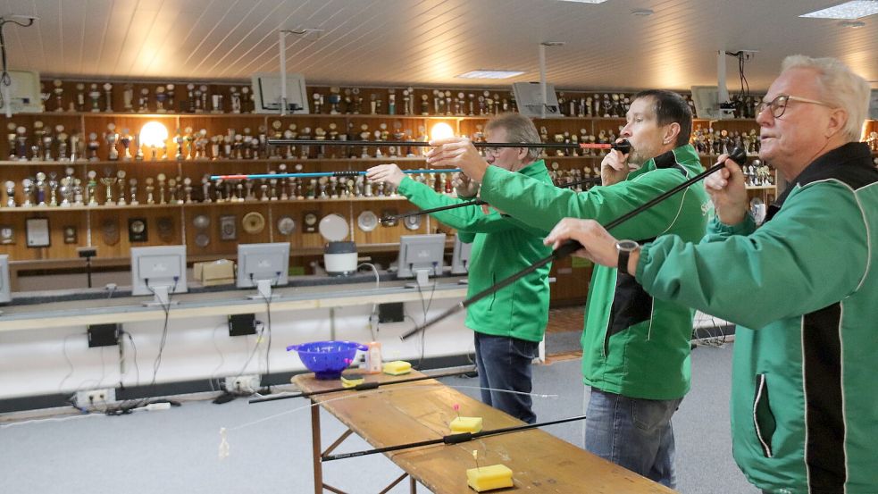Heinz-Werner Müller (von links), Günter Janssen und Alfred Dettmers legen die Blasrohre an. Der Pfeil wird zuvor in das Mundstück eingelegt. Foto: Karin Böhmer