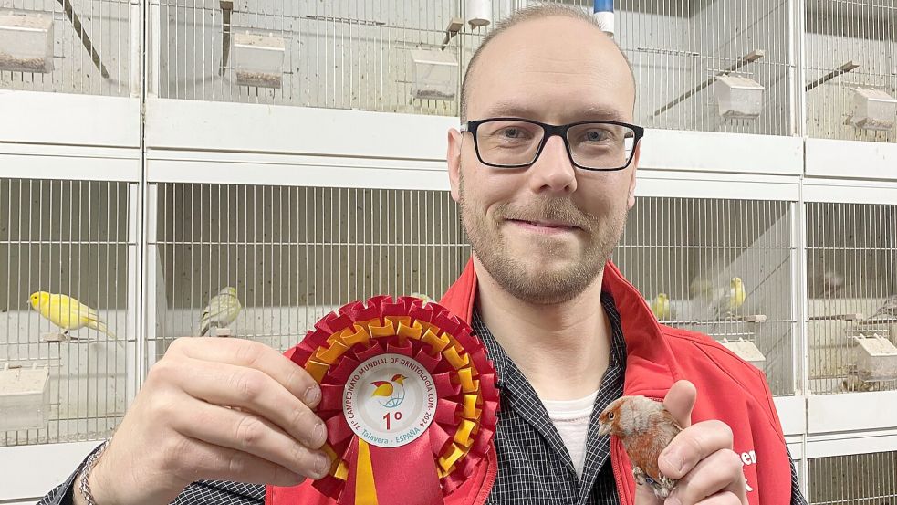 Sichtlich stolz präsentiert Carsten Reck seinen Weltmeister-Vogel und die Siegerschleife. Foto: Holger Janssen