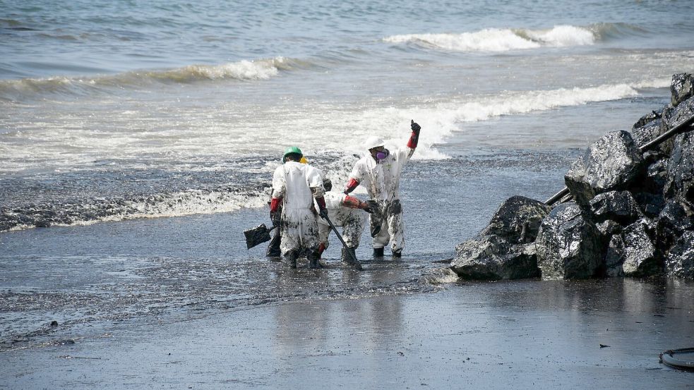 Arbeiter beseitigen einen Ölteppich, der den Strand von Rockly Bay in Scarborough im Südwesten Tobagos erreicht hat. Foto: Akash Boodan/AP/dpa