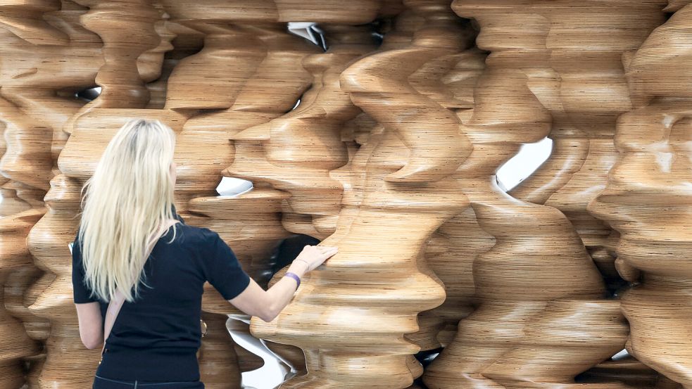 Kunst anfassen erlaubt! Eine Ausstellungsbesucherin berührt die Holzplastik „Lost in thoughts“. Foto: picture-alliance/dpa