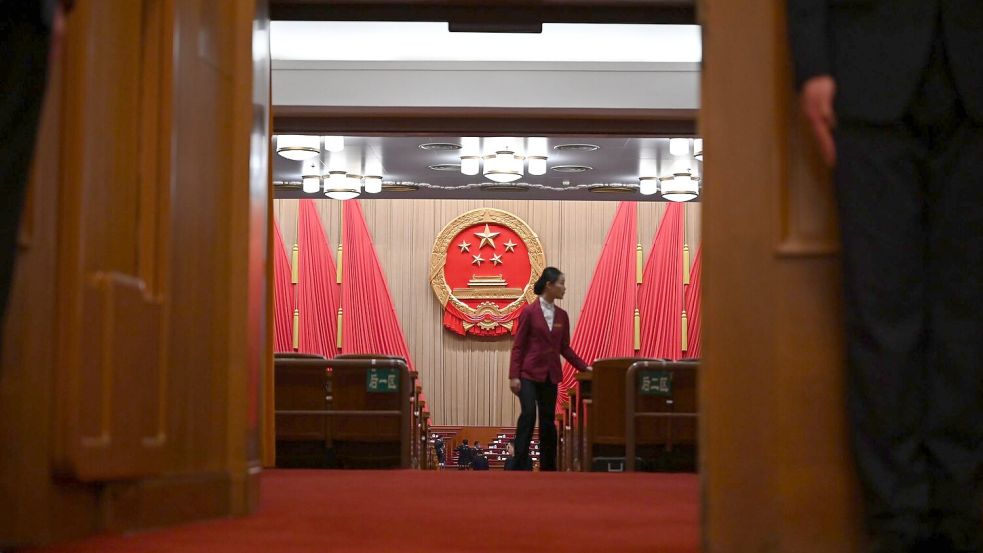 Eine Frau geht durch den Plenarsaal der Großen Halle des Volkes in Peking. Chinas Wirtschaft soll nach dem Willen der Regierung in diesem Jahr um „rund fünf Prozent“ wachsen. Foto: Johannes Neudecker/dpa