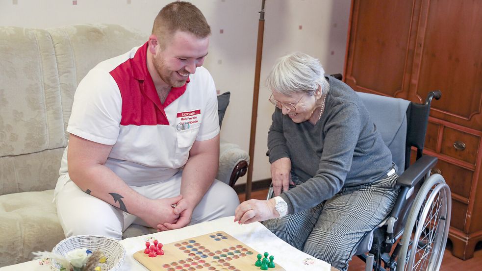 Auch eine Partie „Mensch ärgere Dich nicht“, wie hier mit Bewohnerin Wilma Ebenkamp, gehört für Maik Frerichs zum Beruf als Pfleger hier und da mit dazu. Foto: Romuald Banik