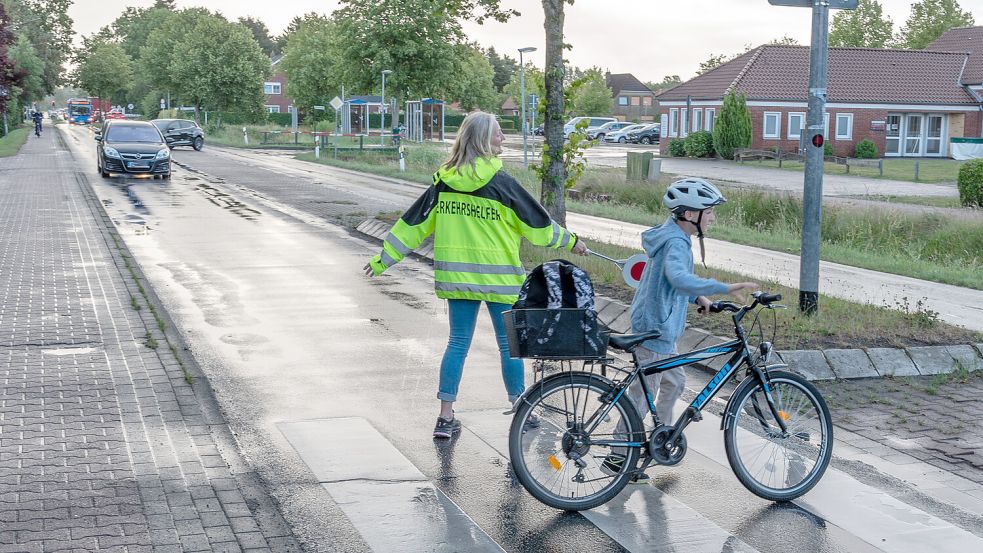 Beschützt von Verkehrshelferin Tina Uphoff quert im vergangenen Sommer ein Kind auf dem Weg zur Grundschule die Straße in Rechtsupweg. Foto: Folkert Bents