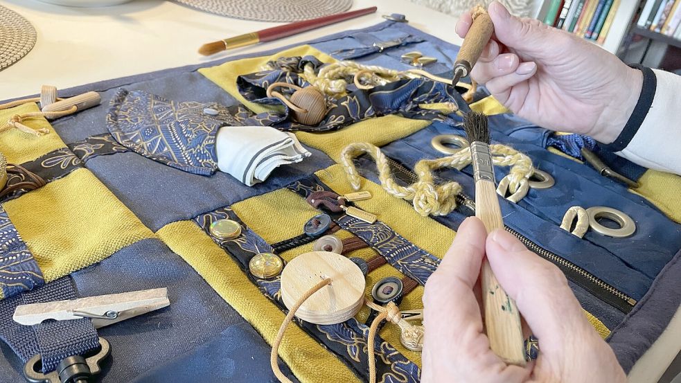 Die Nesteldecke hat Brigitte Simon für ihren Mann um Dinge ergänzt, die er aus seiner Werkstatt kennt: einem Pinsel und kleinen Werkzeugen. Tasten, fühlen, die Motorik üben fällt damit leichter. Foto: Janßen