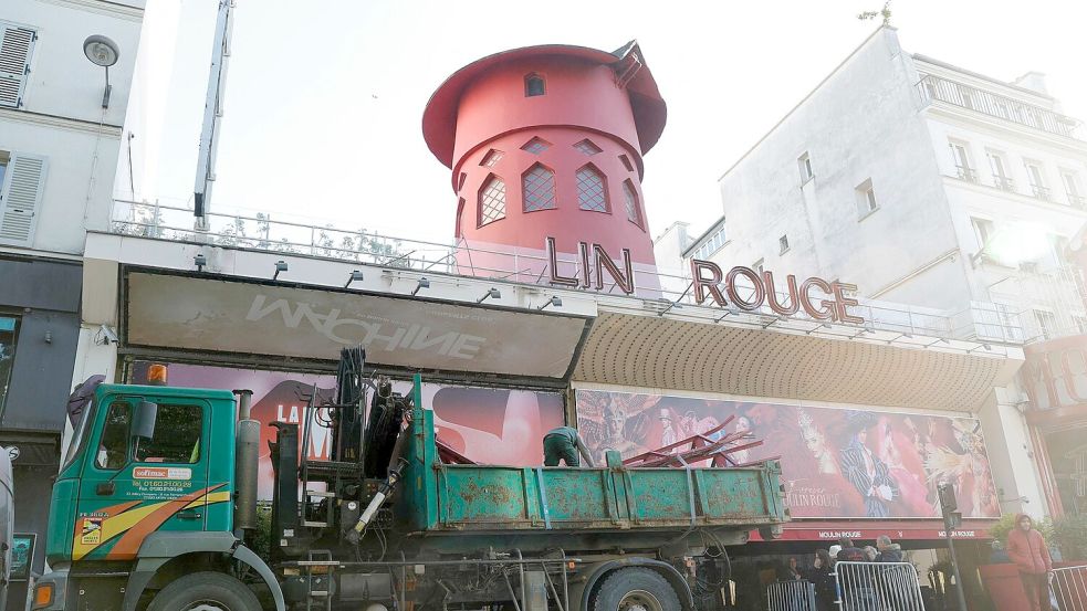 Arbeiter sichern den Bereich vor dem Kabarett, nachdem die Flügel des Windrads des „Moulin Rouge“ in der Nacht abgestürzt sind. Foto: Geoffroy Van Der Hasselt/AFP/dpa