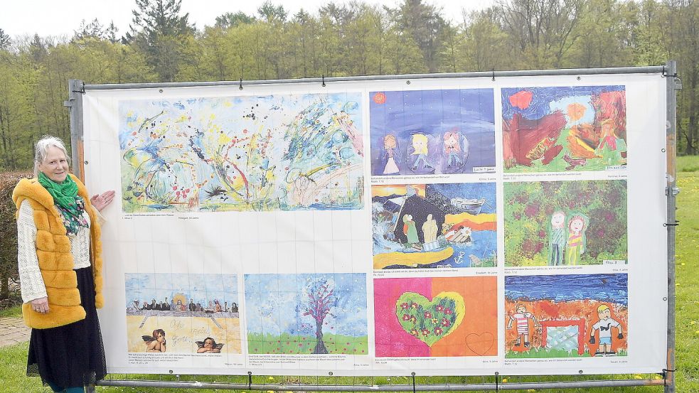 Künstlerin Hildegard Sjoukje Uken vor einer der Bildplane. Das Bild oben links hat sie selbst gemalt. Bildunterschrift „und der Geist Gottes schwebte über dem Wasser“ 1. Mose, 2. Foto: Gerd-Arnold Ubben