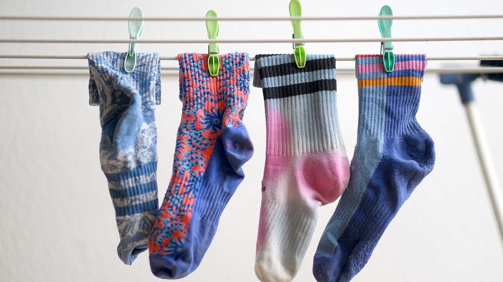 Bunte Socken hängen auf einem Wäscheständer. Am 9. Mai ist Tag der verschwundenen Socken. Foto: Robert Michael/dpa
