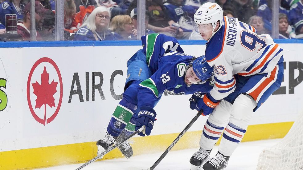 Quinn Hughes von den Vancouver Canucks wird von Ryan Nugent-Hopkins von den Edmonton Oilers zu Fall gebracht. Foto: Darryl Dyck/The Canadian Press via AP/dpa
