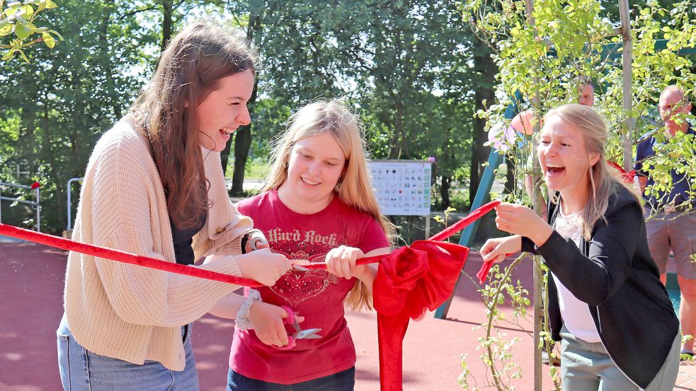 Gute Laune, die ansteckend ist: Die Schülerinnen Neele Koch (von links), Madlene Hattermann und Schulleiterin Nicole Simmet beim Durchtrennen des roten Bandes. Foto: Heino Hermanns