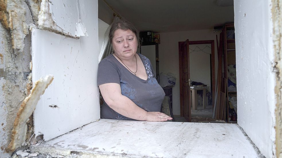Maryna schaut durch das Fenster ihres beschädigten Hauses nach einem russischen Luftangriff auf ihr Wohnviertel in Charkiw. Foto: AP/Evgeniy Maloletka