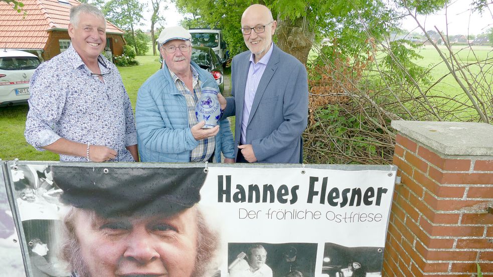 Paul Pützfeld (links) und Holger Neemann (rechts) reichen den Bembel aus dem Nachlass von Hannes Flesner an dessen langjährigen Weggefährten Lübbo „Patent“ Kuske weiter. Foto: Werner Jürgens