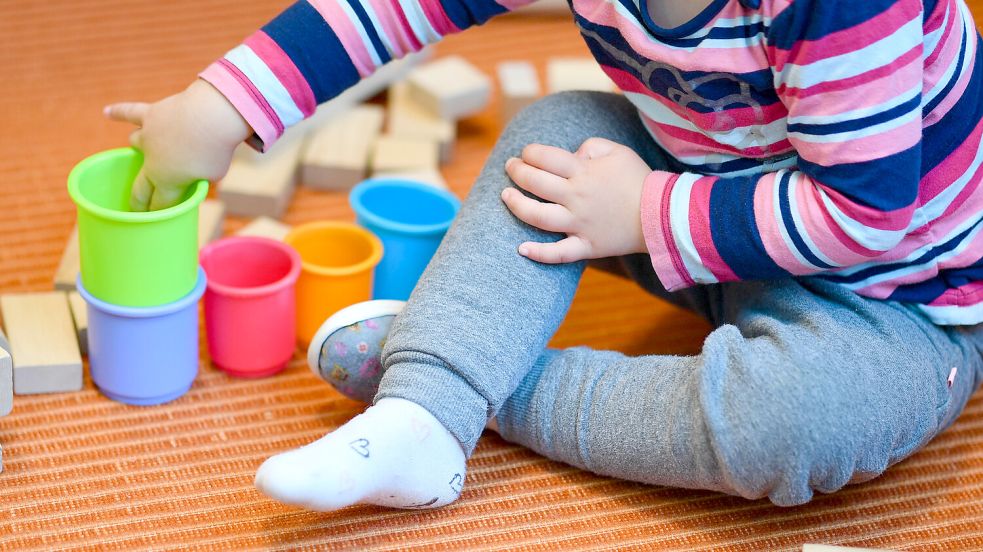 Ein Kind spielt in einer Kita mit Bauklötzen und Stapelbechern. Foto: DPA