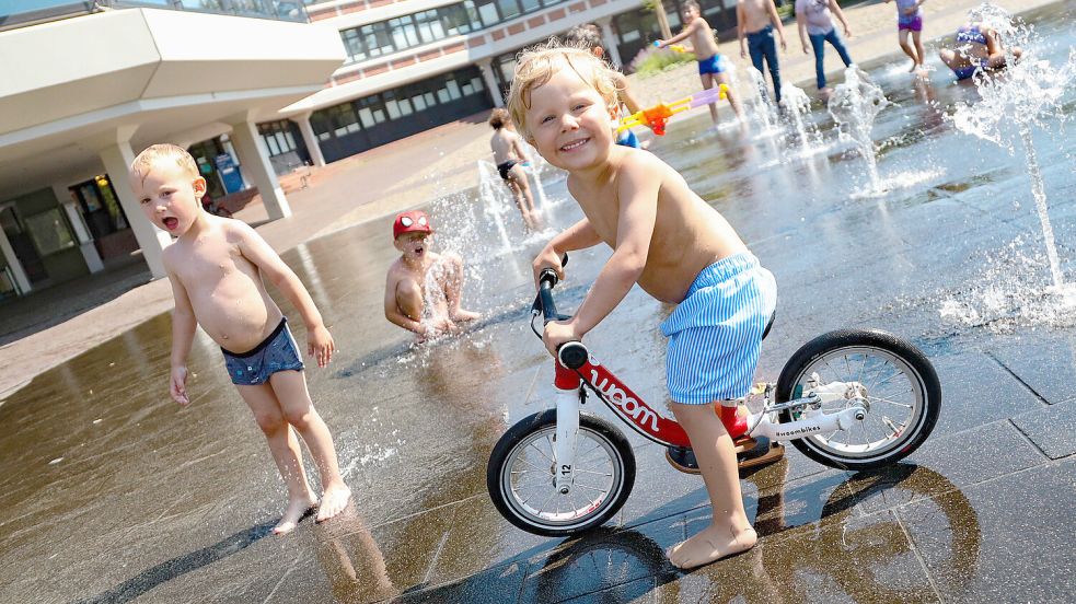 Die dreijährigen Tiziano (vorne) und Elias (links) und der sechsjährige Ben spielten mit einigen Kindern zusammen in den Wasserfontänen am Georgswall. Foto: Romuald Banik