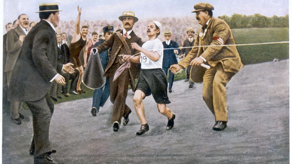Mit letzter Kraft und etwas Unterstützung torkelte der Marathonläufer Dorando Pietri als Sieger ins Ziel. Den Triumph konnte er jedoch nicht lange genießen. Foto: IMAGO/Gemini Collection