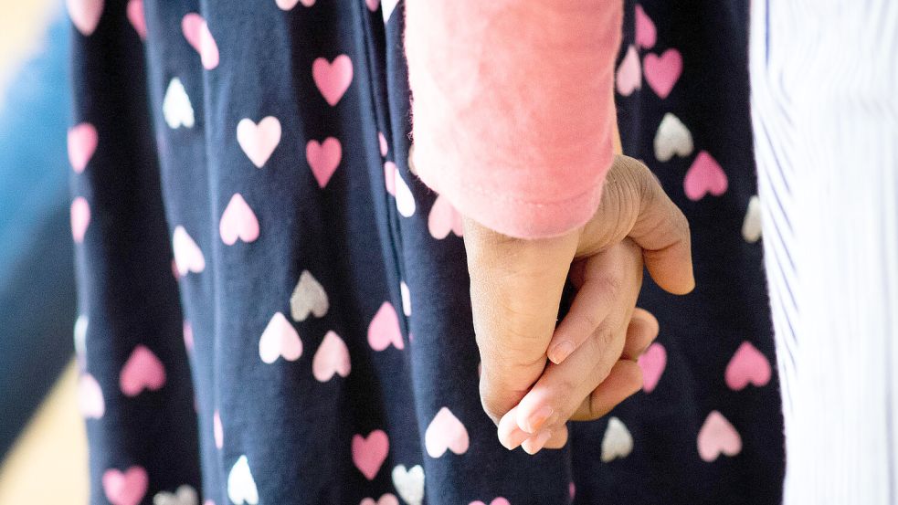 Hand in Hand tanzen Kinder und Erzieherinnen bei einem Bewegungsspiel. Bei Überforderung der Eltern, Vernachlässigung, Misshandlung werden Kinder zum Teil aus ihren Familien herausgenommen. Im Landkreis Aurich ist die Zahl der Inobhutnahmen zuletzt deutlich gestiegen. Foto: Christian Charisius/DPA