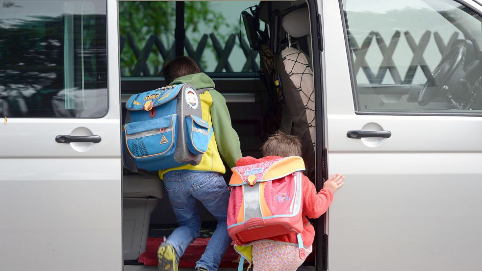 Zwei Schulkinder steigen in ein Auto. Foto: Ralf Hirschberger/DPA