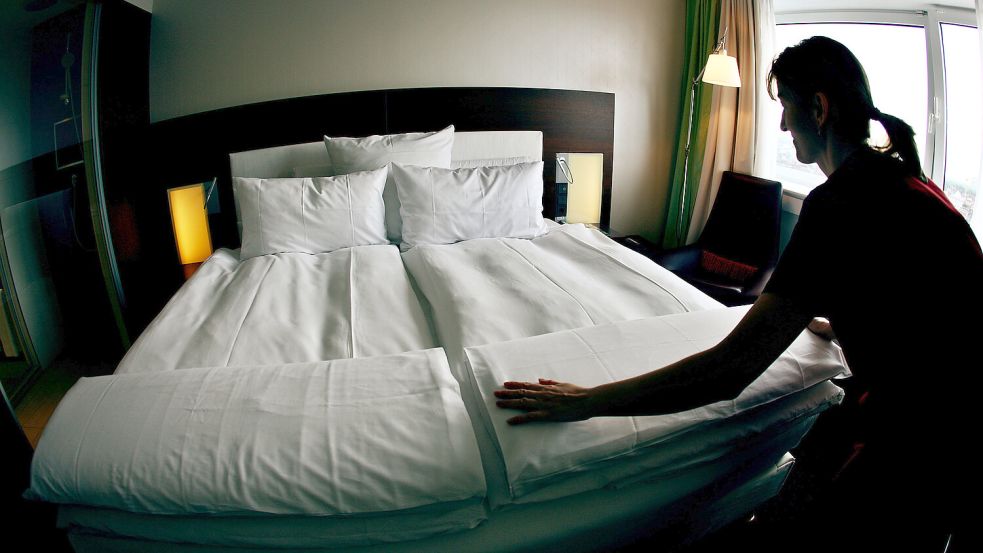 Eine Mitarbeiterin bezieht das Bett in einem Hotelzimmer. Foto: Oliver Berg/DPA