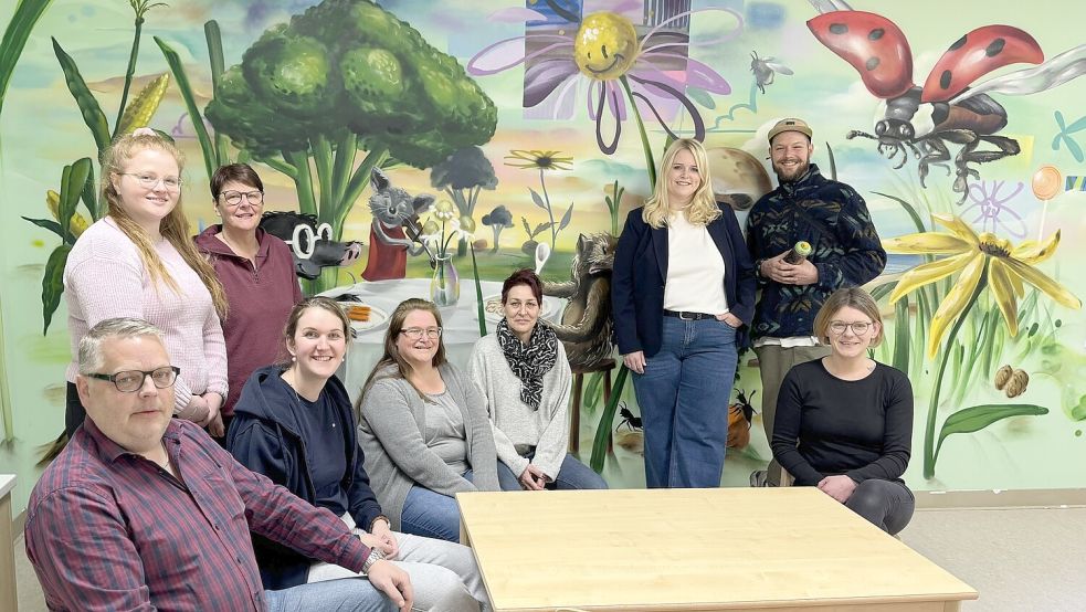 Die Freude über die neue Fantasiewelt ist beim Kita-Team und dem Förderverein groß. Das Bild zeigt Vica Wollf (stehend, von links), Ulrike Kruse-Schröder, Annika Gerdes, Künstler Tim Write, Hermann Peters (sitzend, von links), Lara Meyer, Simone Pabst, Heike Tiersch-Frühling und Julia Raveling. Foto: Holger Janssen