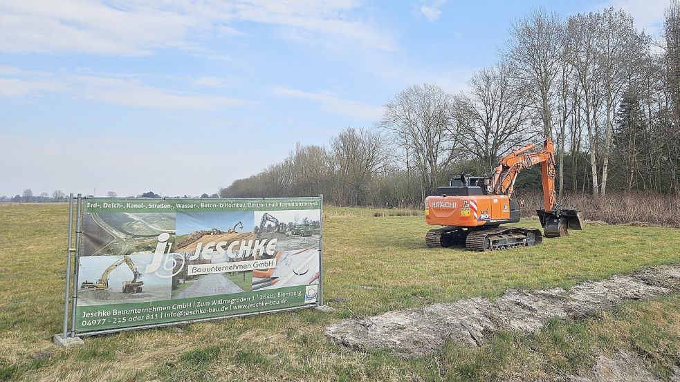 Mit einem Banner neben seinem Bagger wirbt das mit den Tiefbauarbeiten beauftragte Unternehmen am Tjücher Moortun in Marienhafe. Foto: Sarah Dirks