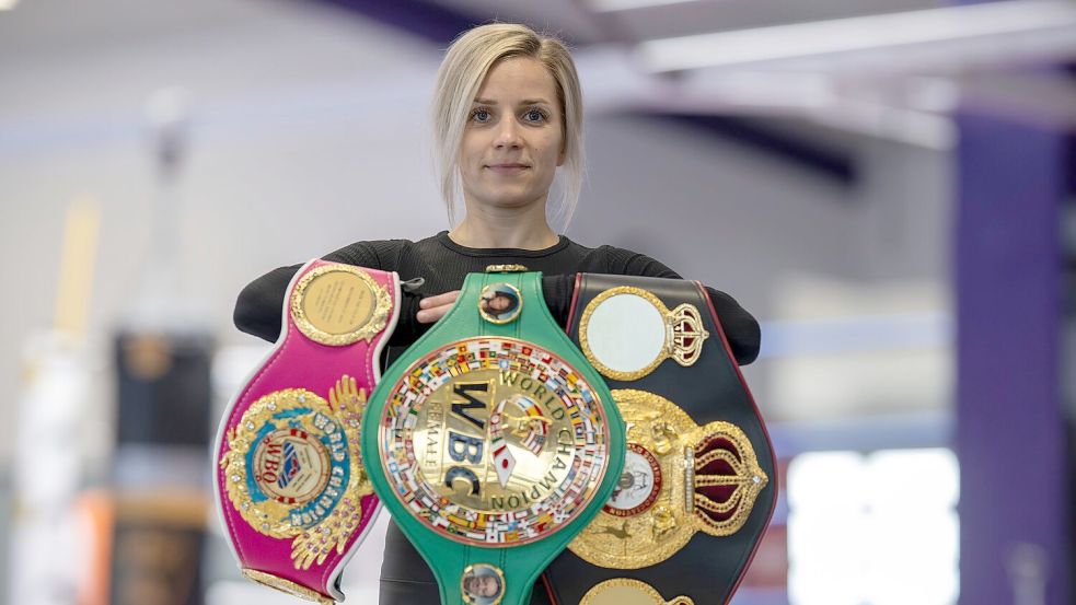 Boxerin Tina Rupprecht mit ihren drei WM-Gürteln - einer fehlt noch. Foto: Peter Kneffel/dpa
